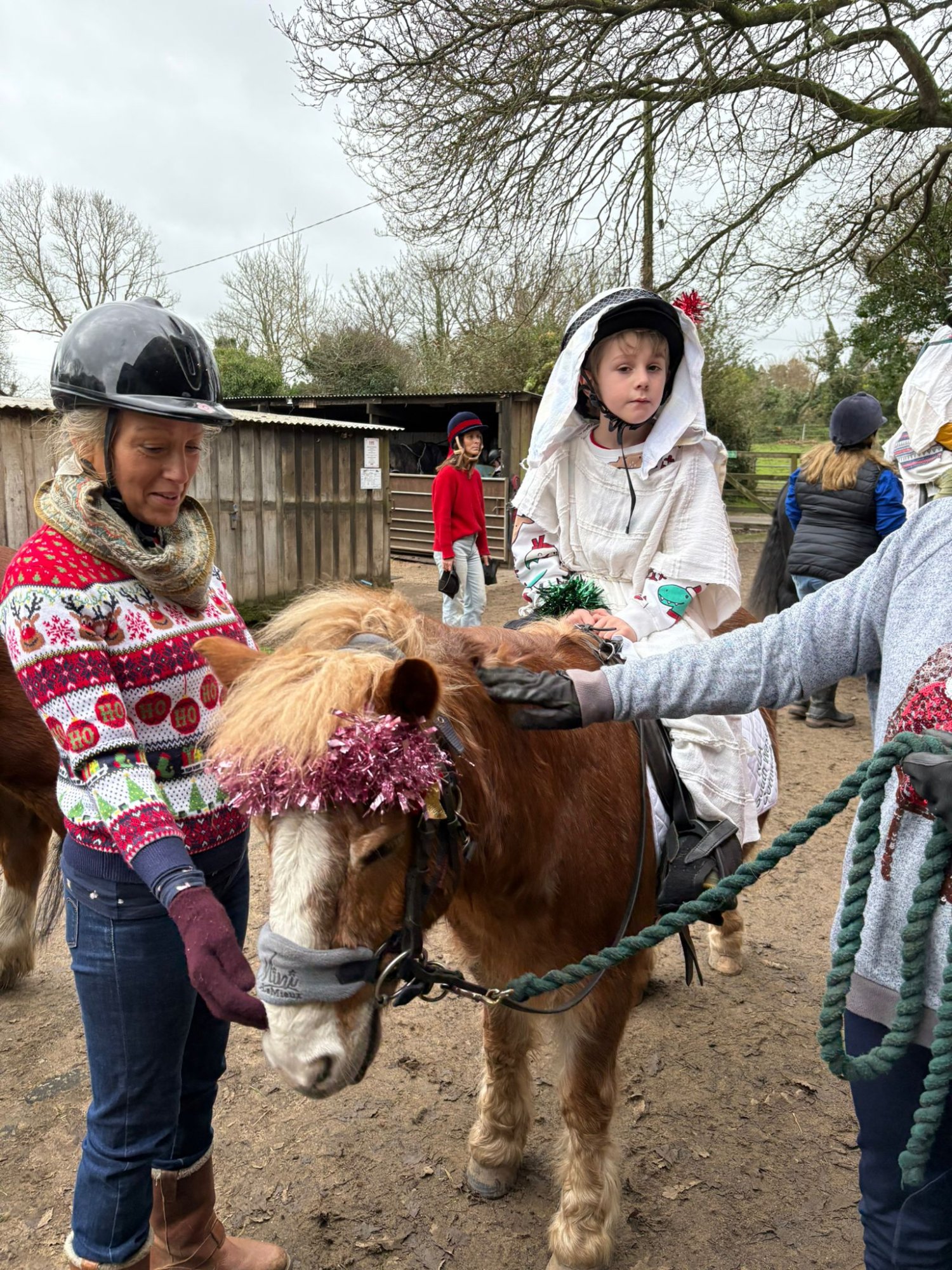 Rider on a decorated pony with volunteers at the Christmas party